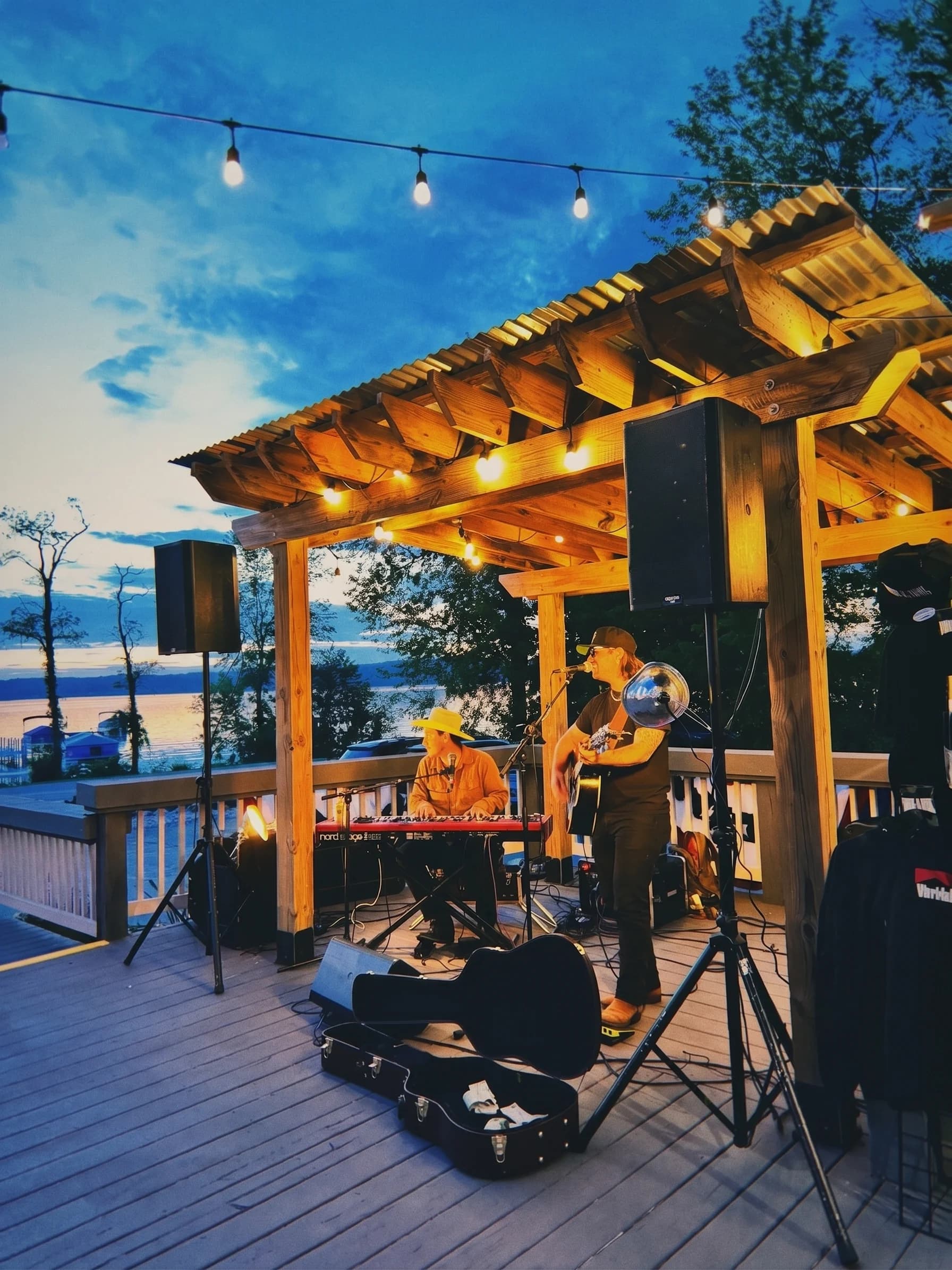 Live music under the pergola at dusk, string lights over the deck